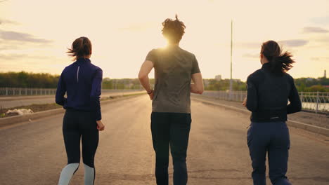 morning-run-outdoors-three-persons-are-running-together-rear-view-of-two-women-and-man